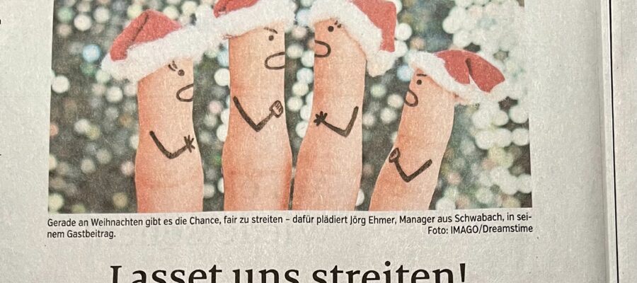 Zeitungsausschnitt, oben ein Bild mit vier Fingern, auf deren Spitzen Weihnachtsmann-Mützen sind und die diskutierende Gesichter aufgemalt haben. Der verpixelte Hintergrund erinnert an den beleuchteten Baum an Weihnachten. Darunter der Bildtext "Gerade an Weihnachten gibt es die Chance, fair zu streiten - dafür plädiert Jörg Ehmer, Manager aus Schwabach, in seinem Gastbeitrag. Man liest darunter die Überschrift des Artikels "Lasset uns streiten!"